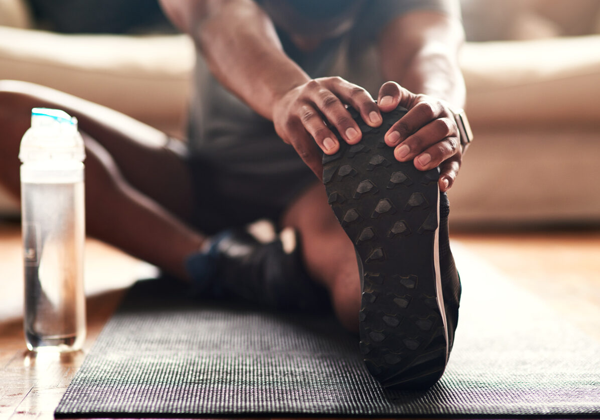 Cropped shot of an unrecognizable young man stretching at home