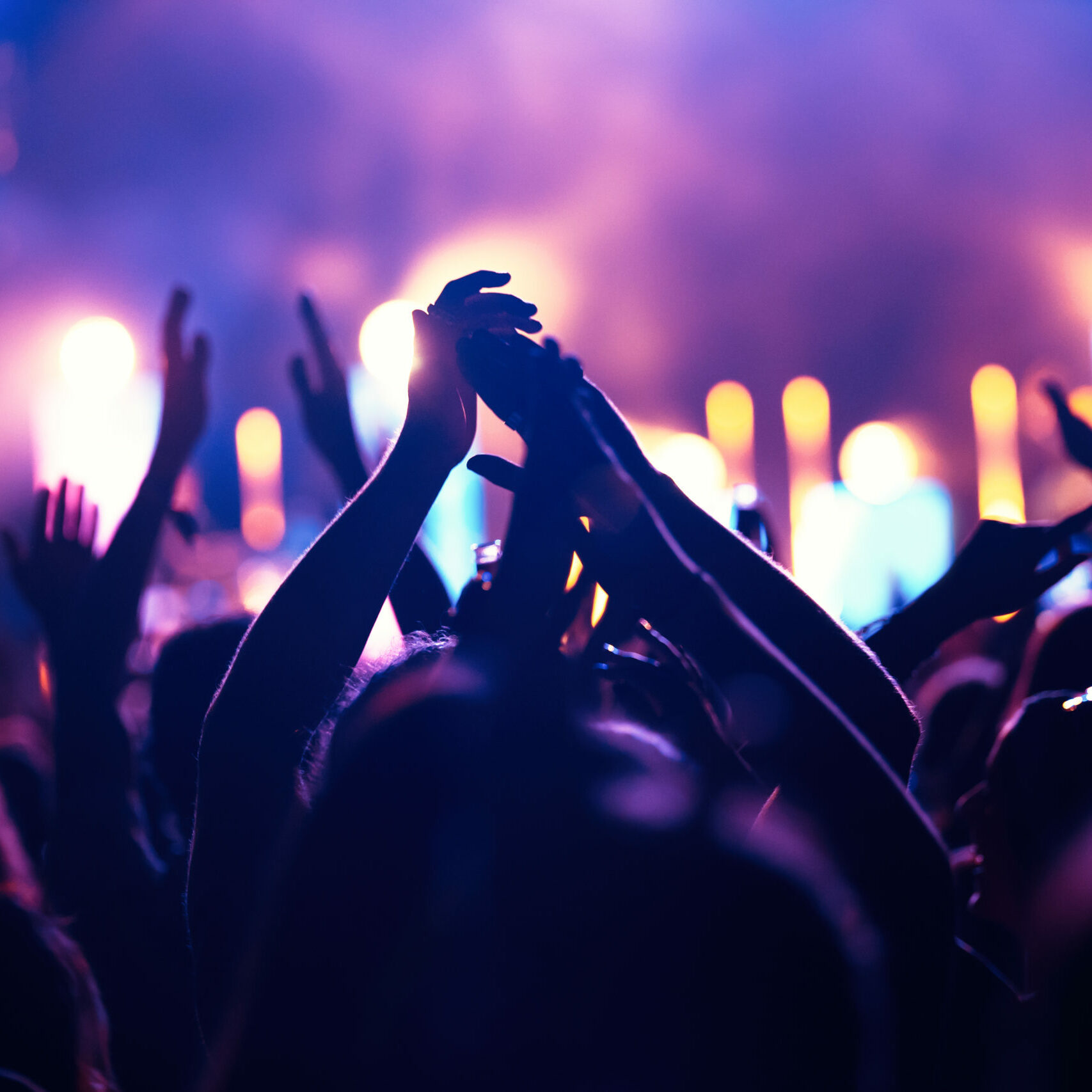 Happy cheering crowd with hands in air at music festival